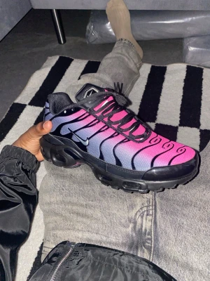 Tn Nike Air Max Plus  rosa/svart/blå  -  Säljer ett par riktigt snygga Nike Air Max Plus i en fet rosa/lila färg (gradient). Använda i max 30 minuter bara för att testa – tyvärr var de för små för mig, annars hade jag lätt behållit dem.   Skick: Som nya (inga slitmärken)  Originalkartong ingår Sjukt bekväma med Air Max-dämpning     Perfekta till både vardag och drip outfits.                      (PRIS KAN DISKUTERAS VID SNABB AFFÄR)