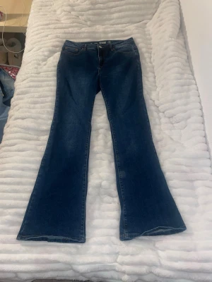 Mörkblå bootcut jeans från Denim 1953 - Säljer ett par mörkblå bootcut jeans från Denim 1953, modell Susan. Jeansen har klassisk femficksdesign, hög midja och utsvängda ben. Tillverkade i slitstark denim med snygga kontrastsömmar. Perfekta för en trendig och avslappnad look.