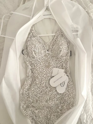 Oanvänd balklänning från Dressroom - Otroligt fin klänning från Dressroom, storlek 36,5. Klänningen är helt oanvänd, endast provad, och förvarad i original-klädöverdrag. Innerklänningen är i champagnefärg och det yttersta lagret är vitt, rikt dekorerat med pärlor och paljetter. Klänningen har ett mycket fint fall och genomarbetade detaljer.🤩  Säljs då jag tyvärr ångrar köpet och Dressroom inte har returrätt vid köp i butik. 
