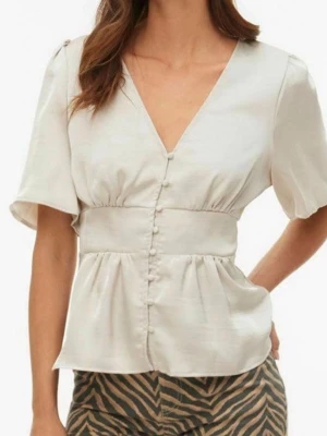Vit blus med v-ringning och knappar - Stilren vit blus med v-ringning och dekorativa knappar framtill. Blusen har korta, puffiga ärmar och markerad midja som ger en feminin siluett. Tillverkad i ett lätt, mjukt material som känns skönt mot huden.