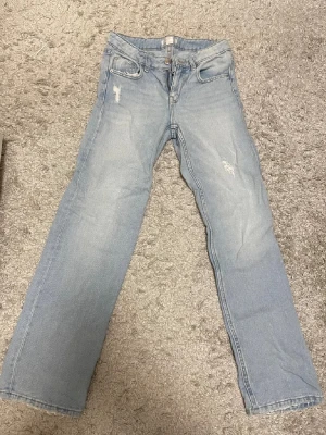 Ljusblå jeans från Gina Tricot - Snyggaste ljusblå jeans från Gina Tricot med klassisk femficksdesign och raka ben. Jeansen har slitna detaljer framtill och stängs med dragkedja och knapp. De är i storlek 152. Perfekt för dig som gillar en avslappnad och trendig look👖✨