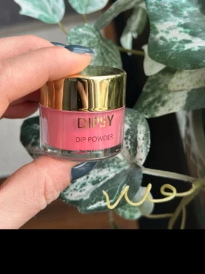 DIPSY Dip Powder röd nagelpulver - Snyggt rött dippowder från DIPSY för naglar. Kommer i en liten burk med guldfärgat lock och är perfekt för att skapa hållbara och trendiga naglar hemma. Pulvret har en intensiv rosa nyans och är lätt att applicera för ett proffsigt resultat.