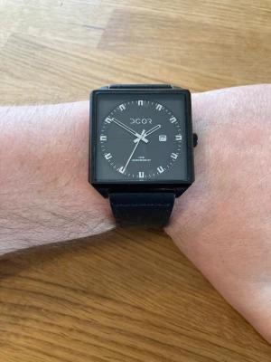 DCOR Kvadratisk 48mm Herrklocka - Säljer en mycket unik DCOR klocka med svart kvadratisk urtavla och svart läderarmband. Klockan har ett japanskt urverk och är vattentålig upp till 3 ATM. Boetten är tillverkad i rostfritt stål. Klockan har en datumvisning. Nära nyskick. Sällan eller aldrig använd. Skick enligt bilder. Behöver nytt batteri.  Nypris: 700 SEK Mitt pris: 389 SEK  Skickas alltid snabbt och spårbart. Skriv vid frågor och se gärna mina andra annonser!   GRATIS: För betalande kunder erbjuder jag personlig experthjälp fö