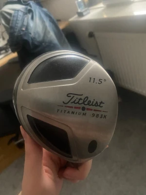 Titleist Titanium 983K Driver - Säljer en Titleist Titanium 983K driver med 11,5° loft. Klubban har en klassisk silverfärgad och svart design med tydliga linjer på träffytan. Perfekt för dig som vill ha en stabil och pålitlig driver i bagen.