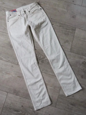 Acne Studio Jeanse - vita - Acne Studios jeans i vitt, tillverkade i Italien av stretchig denim för hög komfort. Låg midja, smala ben och slim fit. Blixtlåsgylf och 5-ficksdesign. Storlek 30/32 med följande mått: Midja 39-40 cm x2, innersöm 81 cm, ytterben 105 cm. Nya, men med mindre fläckar från förvaring som bör gå bort vid tvätt.