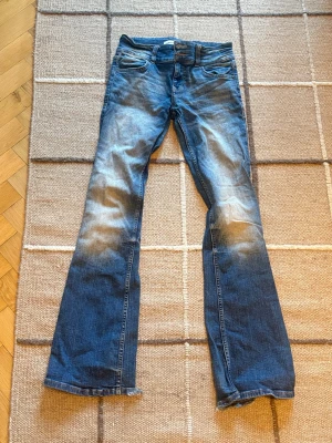 Blå bootcut jeans - Säljer ett par blå bootcut jeans med ljusa partier på låren och knäna. Fråga mig gärna frågor!