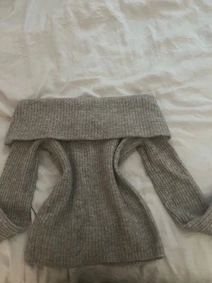 Grå off shoulder stickad tröja H&M - Säljer en ribbstickad brun off shoulder-tröja från H&M. Tröjan har bred krage som kan vikas ner över axlarna och långa ärmar. Perfekt för dig som vill ha en trendig och mysig look till hösten eller vintern.