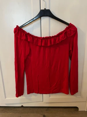 Röd offshoulder topp med volang - Superfin röd offshoulder tröja som är super skön och perfekt nu till våren. Har varit en av mina favorit tröjor då den är extremt skön och dessutom väldigt fin. Pris kan diskuteras. Obs! Köparen står för frakt.
