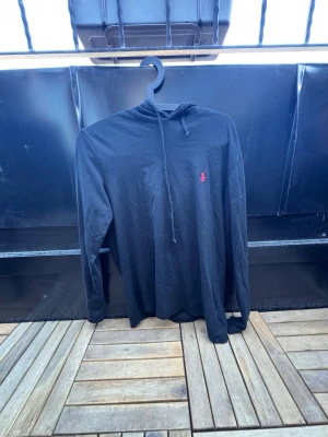 Svart hoodie från Ralph Lauren🙌🤩 - Svart hoodie med lång ärm från Ralph Lauren. Klassisk design med dragsko i huvan och den ikoniska röda loggan broderad på bröstet. Tillverkad i mjukt bomullstyg, perfekt för en avslappnad och stilren look.