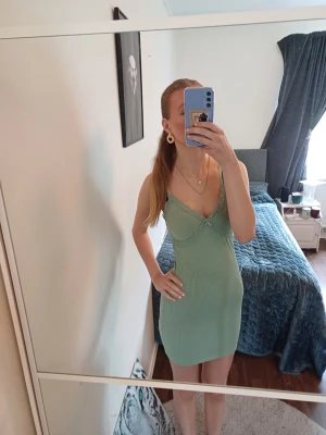 Ljusgrön ribbad kort klänning - Snygg ljusgrön kort klänning med ribbad struktur och spetsdetaljer vid urringningen. Klänningen har tuna axelband och har en figurnära passform som framhäver siluetten. Perfekt för sommaren storlek xs/s, skriv om ni har frågor, priset går att diskutera 