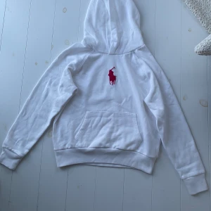 Polo hoodie - Säljer denna helt oanvända polo tröjan med en rosa logga(den ser röd ut på bilden) Jag kan säga att den är sjukt skön och jätte fin! Den är barn storlek 12-14 år. Den har en stor fläck!!