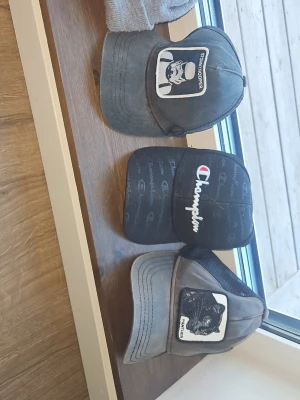 Svarta och gråa kepsar Champion & Goorin Bros - Säljer tre kepsar: en svart Champion-keps med broderad logga, en grå Goorin Bros-keps med svart panter-patch och mesh baktill, samt en svart keps med Stormtrooper-märke även en grå-dickies mössa.  Alla har böjd skärm och justerbar passform. Mer bilder📸 pris💸 info📃 tveka inte på o skriva till oss. [Säljes en huvudbonad i taget-flera i taget]