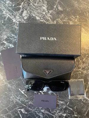 Prada Solglasögon - Helt nya svarta par solglasögon som är perfekt våren och kommande sommarn☀️☀️☀️. Solglasögon kommer med allt som finns med i bilderna och allt fraktas fort!!!!✅😃😃