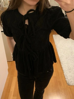 Svart blus från Gina Tricot - Intressekoll på denna jättesöta svarta blusen ifrån Gina Tricot! Blusen har knytning framtill och är i stl XS. Säljer pga kommer inte till användning.