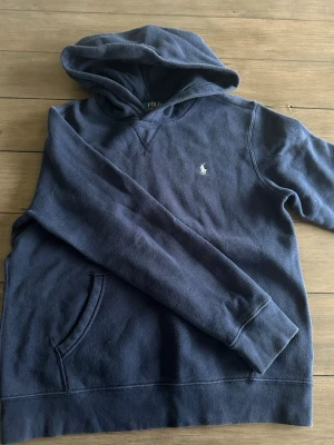 Mörkblå Ralph Lauren Hoodie - Hejsan! Säljer denna mörkblåa Ralph Lauren hoodien då den blivit allt för liten för mig, den har varit använd flertalet gånger och har mindre tecken på användning, annars är den rätt så fräck! Skriv till mig om ni har några funderingar eller frågor! Priset går att diskutera