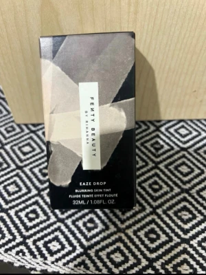 Fenty Beauty foundation nr 10 - Foundation från Fenty Beauty by Rihanna i nyans 10. Kommer i en stilren, geometriskt mönstrad kartong med beige och svarta toner. Perfekt för dig som vill ha en jämn och naturlig bas med lätt till medium täckning.