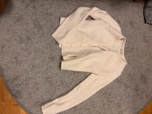 Ljusbeige kofta från Gina Tricot - Ljusbeige kofta från Gina Tricot i mjukt stickat material. Klassisk design med rund halsringning, knappar framtill och långa ärmar. Perfekt att slänga över en topp för en chill look. Lite nopprig men inget som syns därav priset. Nypris 399