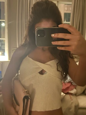 Trendig Zara topp - Trendig vit croppad linnetopp med twistad detalj framtill och liten cut-out. Toppen är ribbad och ärmlös, perfekt för en modern och stilren look. Passar till både jeans och kjol för en cool outfit.