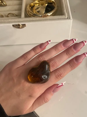 Guld ring med brun sten - Säljer denna jättefina guldpläterade ring med en brun sten från pilgrim! Den är justerbar så man behöver inte tänka på någon storlek!