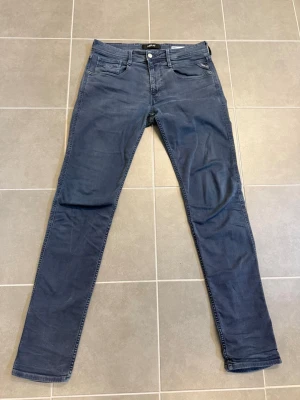 Blå slim fit jeans från Replay W33 L36 - Snygga blå slim fit jeans från Replay med klassisk femficksdesign och diskret logga på myntfickan. Jeansen har en modern passform och är tillverkade i mjukt denimtyg med lite stretch för extra komfort.