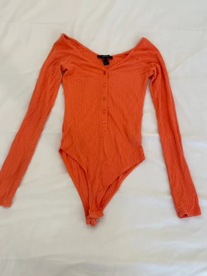 Orange body från Forever 21 - Säljer denna orangea bodyn från Forever 21 med långa ärmar som inte används🫶🏼🫶🏼xs-s