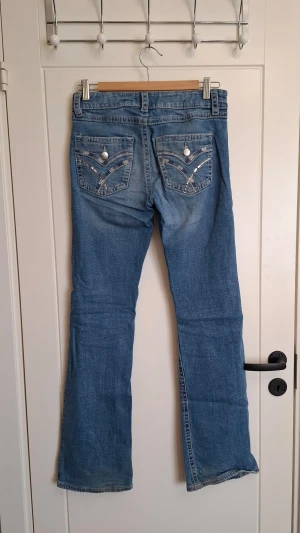 Blå jeans med dekorerade bakfickor - Säljer ett par blå jeans från Gina Tricot med snygga dekorationer på bakfickorna. Jeansen har klassisk femficksmodell, raka ben och är gjorda i ett slitstarkt denimtyg. Perfekta för dig som vill ha en cool och avslappnad stil.