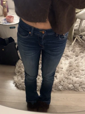 Mörkblå bootcut jeans från LTB - Snygga mörkblå bootcut jeans från LTB med klassisk femficksdesign och orangea sömmar. Jeansen har normal midja och är tillverkade i ett stretchigt denimtyg som sitter tajt över låren och släpper ut lite vid bensluten. Perfekta för en trendig och avslappnad look.