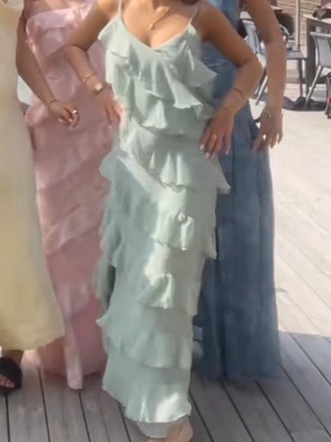 Ljusgrön balklänning - Supersnygg ljusgrön långklänning med tunna axelband och flera lager volanger. Den är väldigt passande till bal och även stora event. 