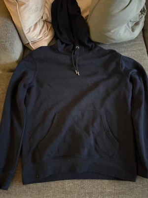 Svart hoodie från Primark Cares - En enkel och stilren svart hoodie från Primark Cares med huva och dragsnören. Hoodien har en stor magficka framtill och är gjord i mjukt material, perfekt för chill dagar. Passar dig som gillar basic streetwear och vill ha något bekvämt.