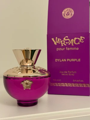 Versace Dylan Purple EdP 100ml - Versace Dylan Purple pour femme är en lyxig parfym i en rund, lila glasflaska med guldfärgade detaljer och Medusa-emblem. Flaskan rymmer 100 ml Eau de Parfum och har en elegant, exklusiv design som verkligen sticker ut på parfymhyllan.