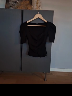 Bubbleroom svart ribbad topp med rynkdetalj och snygg urringning strl XS - Bubbleroom svart ribbad topp med rynkdetalj och snygg urringning strl XS. Passar även till S! Använd 1 gång, mycket fint skick. Perfekt för både utgång och ha på sig till skolan/vardadan❣️ missa inte mina andra annonser❣️