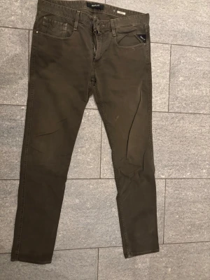 Olivgröna Anbass jeans från Replay - Snygga olivgröna jeans från Replay i modellen anbass. Klassisk femficksmodell och diskreta sömmar. Jeansen har en modern look och är tillverkade i ett mjukt bomullsmaterial med lite stretch för extra komfort.