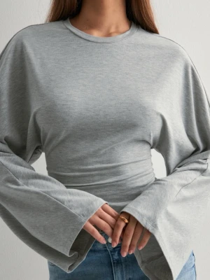 Grå topp med vida ärmar - Trendig grå croppad topp med rund halsringning och extra vida, långa ärmar. Tillverkad i mjukt bomullsmaterial som ger en avslappnad men snygg look. Perfekt att matcha med jeans eller kjol för en cool vardagsstil.