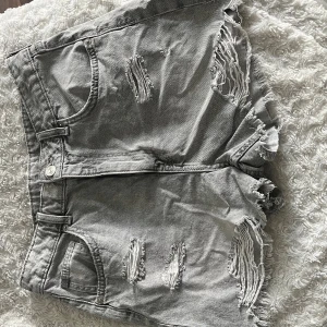 Gråa ripped jeansshorts Divided H&M - Säljer ett par gråa jeansshorts från Divided H&M i storlek 40. Perfekta för sommaren!