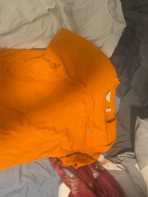 Orange t-shirt från GANT - Säljer en orange t-shirt från GANT med klassisk passform och korta ärmar. T-shirten har en liten logotyp på bröstet och är tillverkad i mjuk bomull. Perfekt för dig som gillar färgstarka plagg och enkel stil.