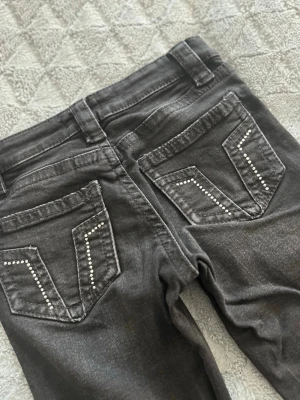 Svarta jeans med nitar på fickorna - Säljer ett par svarta jeans med snygga. Jeansen kommer från Gina tricot. Jeansen är använd endast få gånger. Materialet är mjukt denim som sitter skönt och passar till många olika stilar.