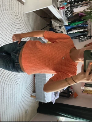Orange ribbad topp med kort ärm - Säljer en orange ribbad topp med korta ärmar och rund hals. Toppen har en croppad passform. Perfekt till jeans eller kjol för en trendig look.