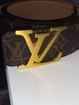 Ett snyggt bälte med en uniq design L och en V - En snygg brunt bälte med guldiga skarp jätte snygg passar nästan med allt, passar jätte bra och  jätte bra kvalité