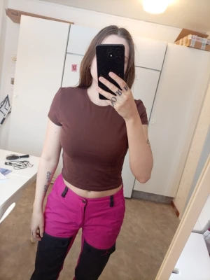 Brun croppad t-shirt - En enkel brun croppad t-shirt med korta ärmar och rund halsringning. Perfekt för dig som gillar en avslappnad och trendig stil. Materialet känns mjukt och bekvämt mot huden.