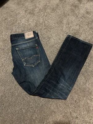 Mörkblå jeans från Replay storlek W34 L34 - Storlek w34 L34 Snygga mörkblå jeans från Replay med klassisk femficksdesign och raka ben. Jeansen har tydliga kontrastsömmar och en patch med Replay-logga bak i midjan. Perfekta för dig som gillar en tidlös och stilren look.
