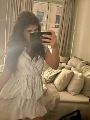 Blå volangklänning med v-ringning - Säljer en ljusblå klänning med volanger och v-ringning. Klänningen har korta ärmar och en luftig, lätt form som ger en romantisk känsla. Perfekt för varma dagar och har en feminin siluett.