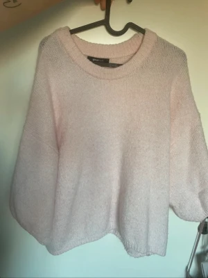 Ljusrosa stickad tröja Gina Tricot - Mysig ljusrosa stickad tröja från Gina Tricot med rund halsringning och avslappnad passform. Tröjan har långa ärmar och är tillverkad i ett mjukt, fluffigt material som känns skönt mot huden. Perfekt för lager på lager och en söt vardagslook.