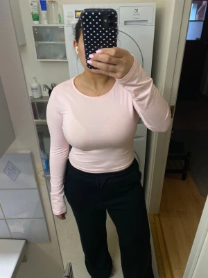 Ljusrosa långärmad topp - En enkel och stilren ljusrosa långärmad topp med rund halsringning. Toppen har en tight passform och är perfekt att matcha med jeans eller mjukisbyxor. Materialet är mjukt och stretchigt, vilket gör den bekväm att bära hela dagen. Aldrig använd men har ej prislapp kvar 