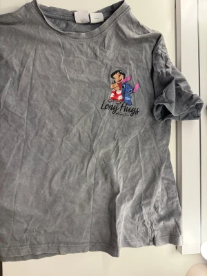 Grå Lilo & Stitch t-shirt - Säljer en lilo&stitch T-shirt för 40kr. Pris kan ju såklart diskuteras. T-shirten kommer från Zara och är i storleken 140cm. Inget tecken på användning. Hoppas ni vill köpa!❤️