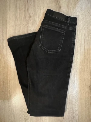 Svarta bootcut jeans low waist - Svarta Low waist jeans från BikBok. Storlek S med längd 31. Strecthiga i materialet. De är använda och färgen har nöts och mellan låren, finns på bild men de är fortfarande i gott skick. 
