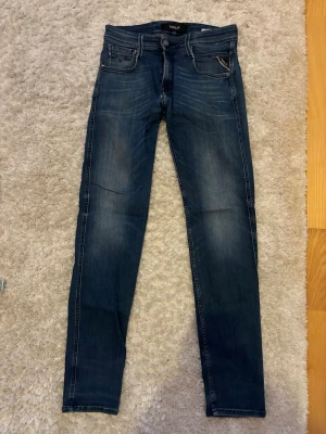 Mörkblå slim jeans från Replay - Säljer ett par mörkblå skinny jeans från Replay med snygga slitningar och klassiska fem fickor. Jeansen har en slim passform och kontrastsömmar. Perfekta för dig som gillar en modern och stilren look. Pris kan diskuteras.