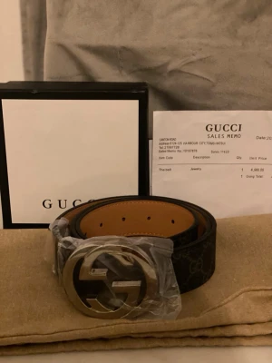 Gucci bälte - Snyggt svart skärp från Gucci med det ikoniska dubbla GG-spännet i silverfärgad metall. Skärpet har diskret GG-mönster på lädret och insida i brunt. Perfekt accessoar för att lyfta din outfit.