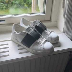 Valentino Garavani Open sneakers vit/svart - Snygga Valentino Garavani Open sneakers i gott skick, dom har lite tecken på användning men inte så man ser de så, (skorna kommer tyvärr inte med box) skorna är 100% äkta , säljer dom för jag ska köpa andra. Dem är i storlek 40 men sitter som storlek 41