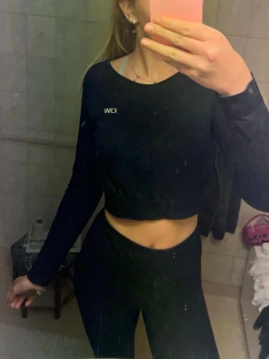 Svart långärmad crop top från ICIW - Snygg svart långärmad crop top från ICIW med tight passform och diskret logga på bröstet. Perfekt för träning eller gymmet, tillverkad i stretchigt material som andas. Matchas enkelt med tights eller andra träningskläder.