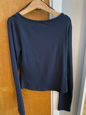 Mörkblå långärmad tröja med öppen rygg - Jättefin mörkblå långärmad topp som är öppen i ryggen. Den är ifrån Ginatricot Young i storlek 146/152. Den är aldrig andvänd.